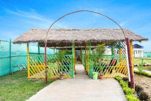 a small hut with a thatched roof and a pathway at Hotel O Mango Leaf Hotel & Restaurant in Baharampur