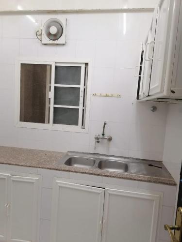 biała kuchnia ze zlewem i oknem w obiekcie شقق الاحلام الذهبية 