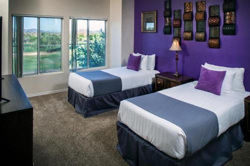 a hotel room with two beds and a purple wall at Luxury Vacation Rentals by Meridian CondoResorts in Scottsdale