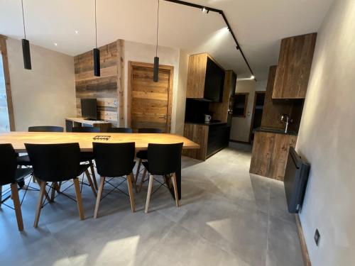 a kitchen with a wooden table and black chairs at Gite Roche Des Ducs avec Piscine toute l'année, Spa, Sauna, Hammam in Rochesson