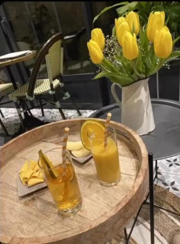 a table with two glasses of juice and a vase of flowers at Les Glycines de Monchy- Chambres d'hôtes in Monchy-Humières