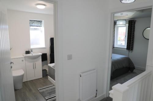 a bedroom with a bed and a sink and a mirror at Modern, Two Double Bedroom House with Free Parking in Chepstow