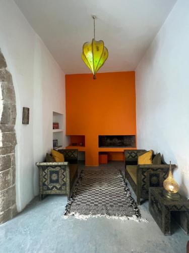 a living room with an orange wall and a hanging banana at Riad Dar Sebta in Essaouira