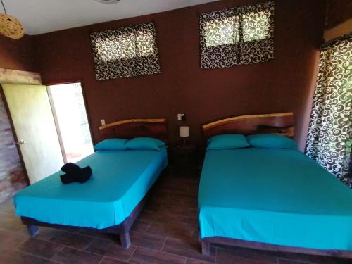 two beds in a room with blue sheets and windows at HOTEL AVE FENIX in Mazunte