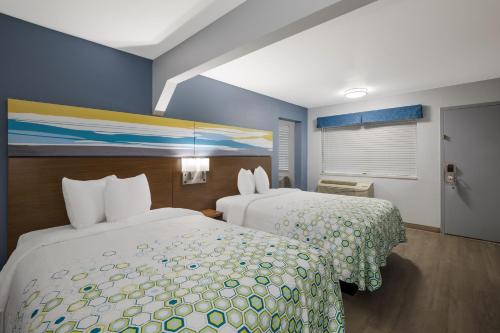 une chambre d'hôtel avec 2 lits et un tableau mural dans l'établissement HomeTowne Studios by Red Roof Orange, TX, à Orange