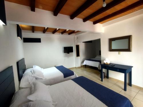 a bedroom with two beds and a desk and a television at Hotel & Hostal Santuario in San Miguel de Allende