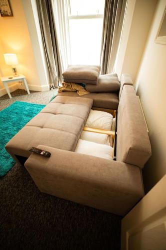 a brown couch in a room with a window at Spacious Sea-View Flat with Easy Invest in Lowestoft