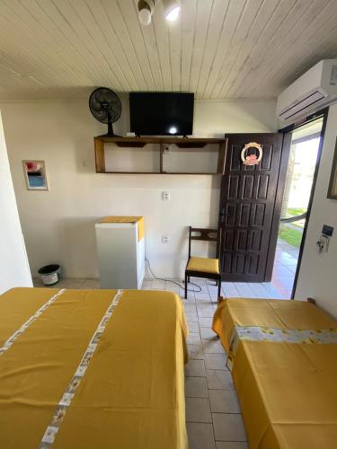 two beds in a room with a tv and a door at Pousada Aventura in Passo de Torres