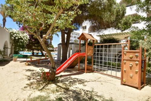 a playground with a slide next to a tree at Hotel Bel Azur Thalasso & Bungalows in Hammamet