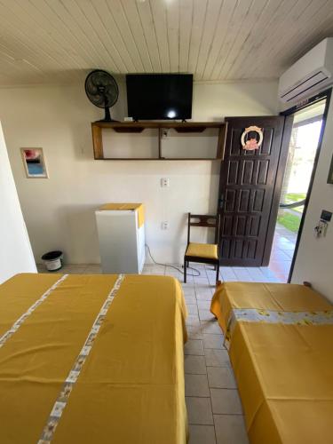 a room with two beds and a tv on the wall at Pousada Aventura in Passo de Torres