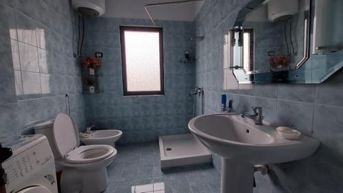 een badkamer met een toilet, een wastafel en een spiegel bij Homemaker in Berat