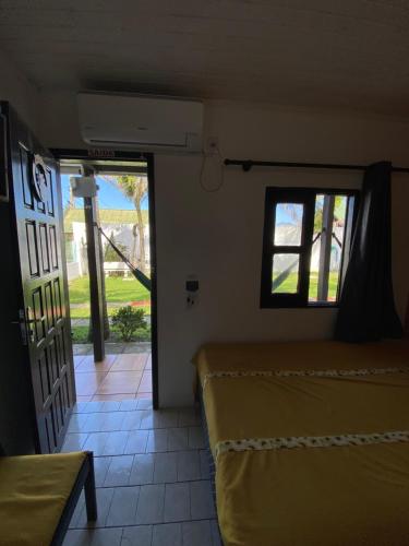 a room with a bed and a door with a window at Pousada Aventura in Passo de Torres