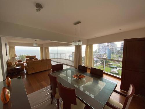 Apartamento Vista al Mar في ليما: غرفة معيشة مع طاولة طعام ونافذة كبيرة