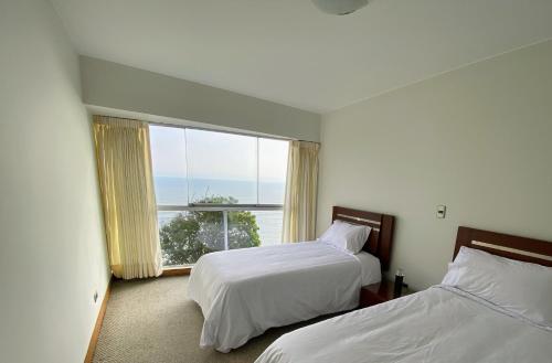 Apartamento Vista al Mar في ليما: غرفة فندقية بسريرين ونافذة كبيرة