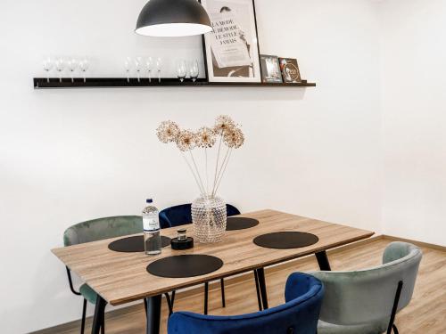 a wooden table with chairs and a vase of flowers at LIGHTPLACE • Design • Boxspring • Balkon • 2 Smart TV •Innenstadt in Braunschweig