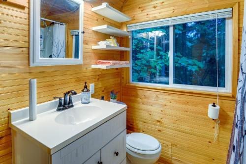 a bathroom with a sink and a toilet and a window at Adorable A-Frame Cabin, Steps to Lake Cushman! in Hoodsport
