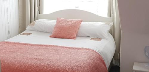 a white bed with a pink pillow on it at Cosy apartment in popular harbour town in Kirkcudbright