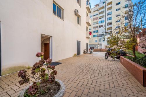 uma calçada de tijolos com uma planta de vaso ao lado de um edifício em Villa Olympia em Durrës