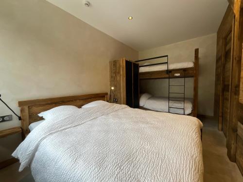 a bedroom with a large white bed and bunk beds at Gite Roche Des Ducs avec Piscine toute l'année, Spa, Sauna, Hammam in Rochesson