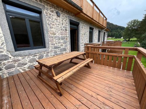 a wooden deck with a bench on a house at Gite Roche Des Ducs avec Piscine toute l'année, Spa, Sauna, Hammam in Rochesson