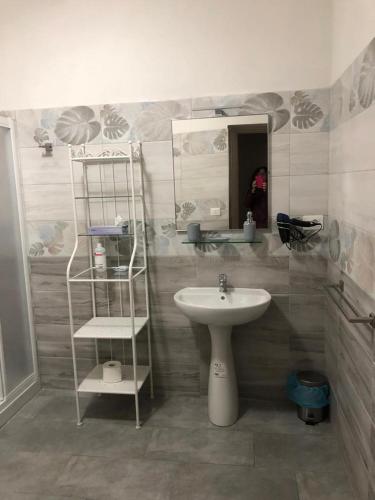 a bathroom with a sink and a mirror and a shelf at Residence il Grappolo di Gavi in Gavi