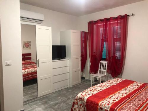 a bedroom with a bed and a tv and red curtains at Residence il Grappolo di Gavi in Gavi