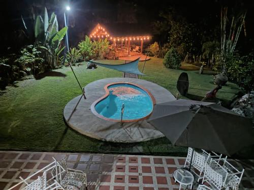a backyard at night with a swimming pool and an umbrella at YETHAN HOUSE in Uvita