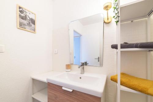 W białej łazience znajduje się umywalka i lustro. w obiekcie le bruit des vagues sur gîte echarou w mieście Port-la-Nouvelle