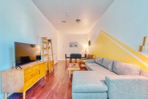 a living room with a couch and a flat screen tv at The Stairway Suites - Convention Center in Philadelphia