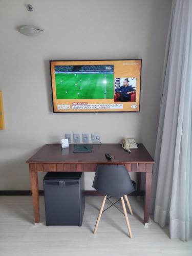 a wooden desk with a television on a wall at Flat Super Luxo Verbo Divino in Sao Paulo