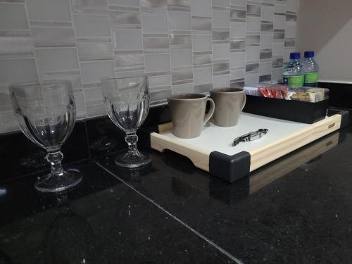 three wine glasses and a tray with a bug on it at Flat Super Luxo Verbo Divino in Sao Paulo