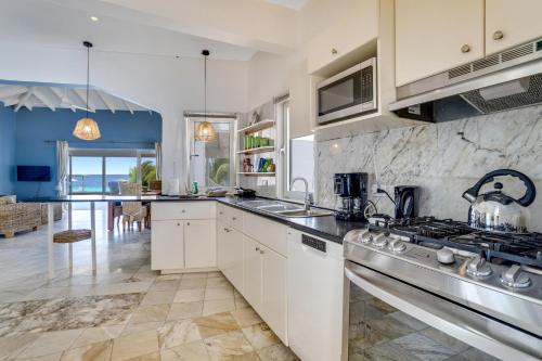 a kitchen with white cabinets and a stove top oven at Oceanfront - Villa Port of Call - in Kralendijk