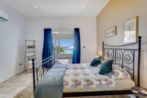 a bedroom with a bed with blue pillows at Oceanfront - Villa Port of Call - in Kralendijk