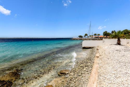 a beach with blue water and palm trees at Oceanfront - Villa Port of Call - in Kralendijk