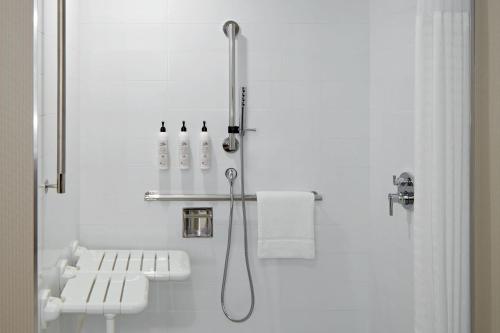 uma casa de banho branca com um chuveiro e um lavatório. em Delta Hotels Calgary Airport In-Terminal em Calgary