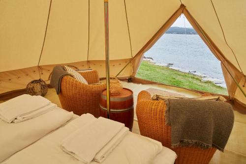 Zelt mit Stühlen und Blick auf das Wasser in der Unterkunft Sandtorgholmen Glamping in Sandtorv