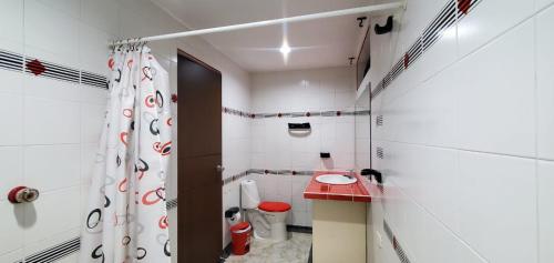 a white bathroom with a toilet and a shower at Hotel El Gran Chaparral in Calarcá