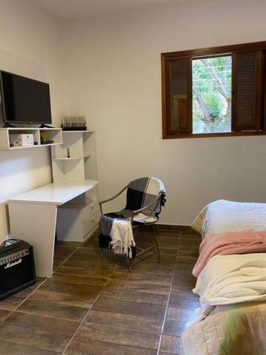 um quarto com uma secretária e uma cadeira ao lado de uma cama em Loft do Sítio São José em Petrópolis