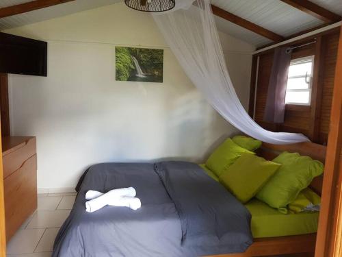 een slaapkamer met een bed met groene kussens en een raam bij le Pitaya in Baillif