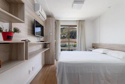 een slaapkamer met een wit bed en een raam bij Cobertura exclusiva com Jacuzzi Privativa no Coração de Itaipava in Itaipava