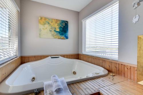 una vasca da bagno bianca in una stanza con finestre di Pet-Friendly Galveston Home with Wraparound Deck a Galveston