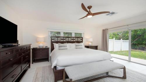a white bedroom with a bed and a tv at Laguna Del Mar in George Town
