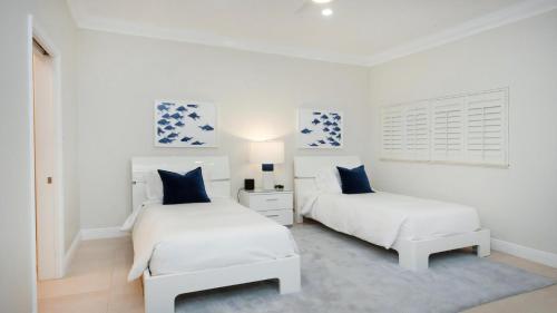 two beds in a white room with blue accents at Laguna Del Mar in George Town
