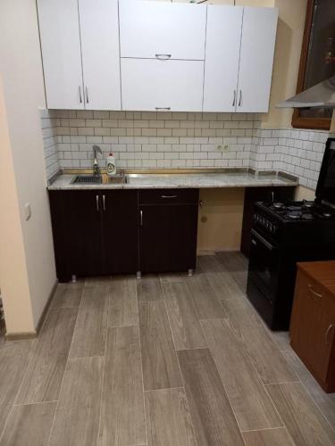 cocina con armarios blancos y suelo de madera en Mados Apartment en Tiflis