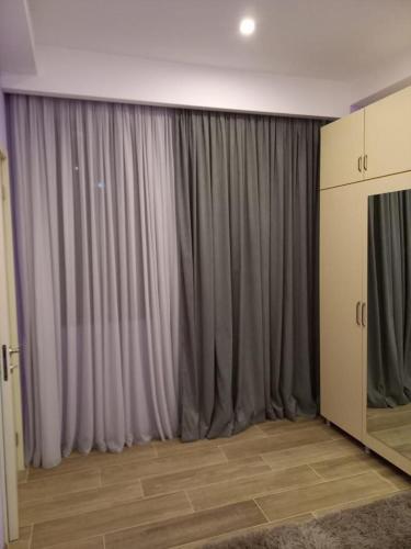 Habitación con cortinas grises y TV. en Mados Apartment en Tiflis