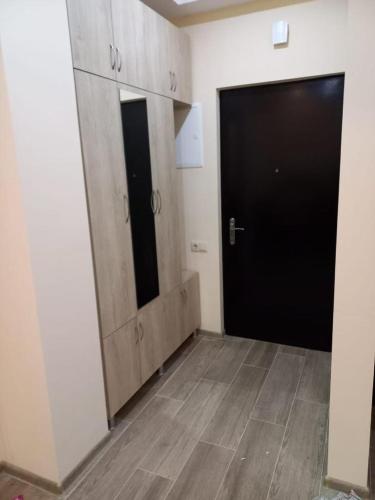 Habitación con puerta negra y armarios de madera. en Mados Apartment en Tiflis