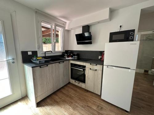 une cuisine avec un réfrigérateur blanc et un évier dans l'établissement Bas de villa Climatisé et wifi 2 chambre pour 4 personnes et petite vue mer, à Pietrosella