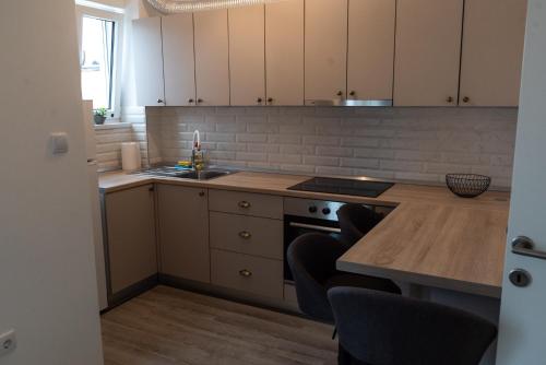 a kitchen with white cabinets and a stove top oven at Lux Apartment III Prijedor in Prijedor