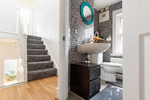 a bathroom with a sink and a toilet and a staircase at Large, Bright and Spacious 3 Bed Flat in London in London