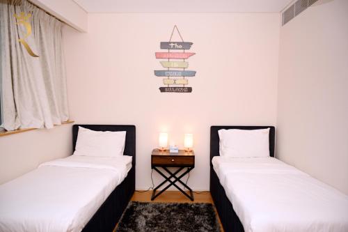 two beds in a room with a table and two candles at Luna Breeze - Elegant 2BR Apartment with Beach Access, Near Al Raha Beach in Abu Dhabi